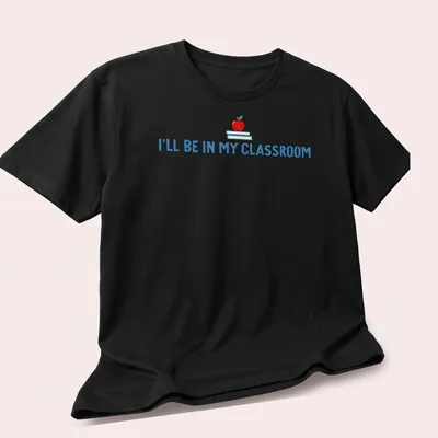 Playful illustration of an apple and books with the text I'll Be In My Classroom — printed on a unisex t-shirt (angled view)