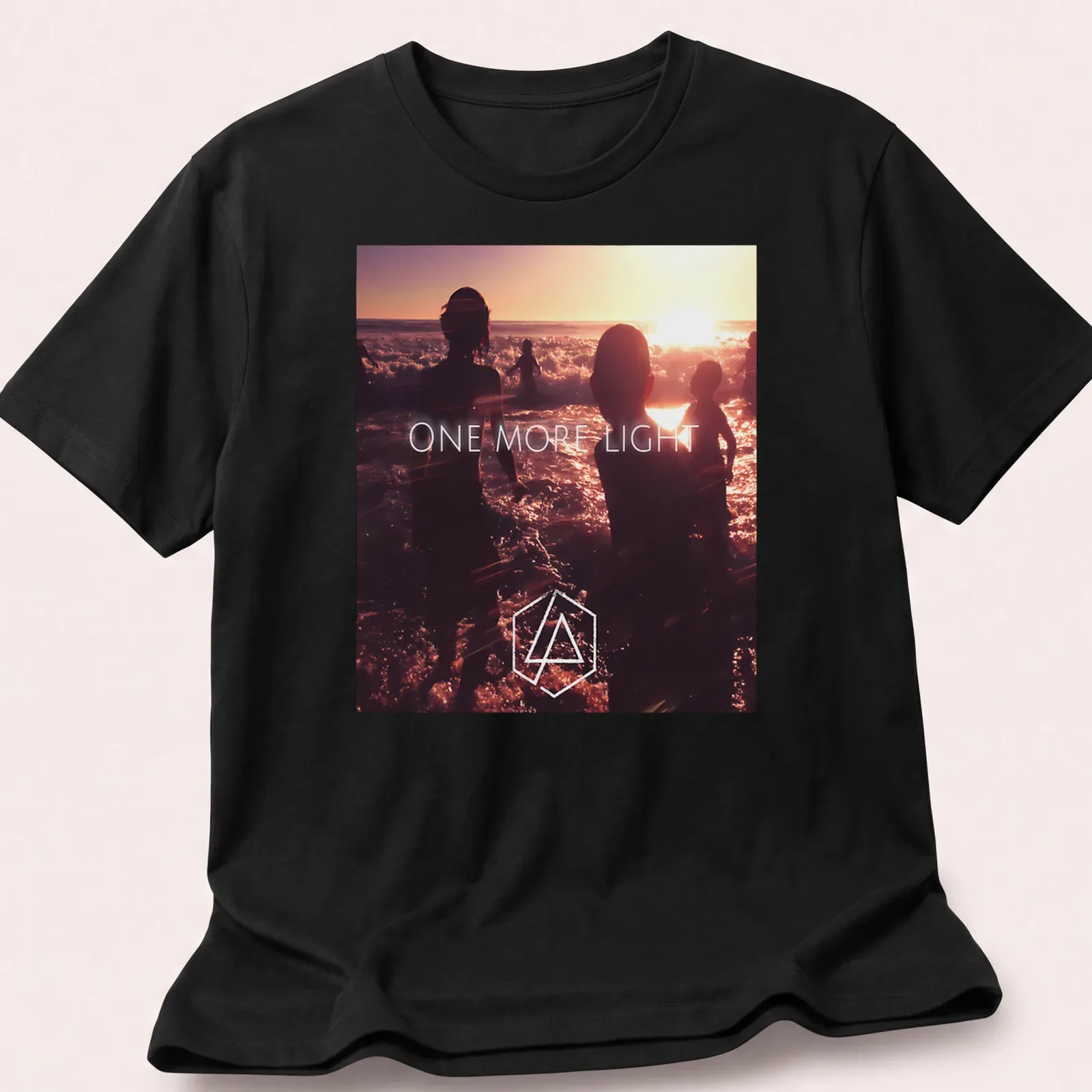 Photographic print of beach silhouettes with 'ONE MORE LIGHT' text in sunset colors. — printed on a unisex t-shirt