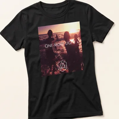 Photographic print of beach silhouettes with 'ONE MORE LIGHT' text in sunset colors. — printed on a women's shirt
