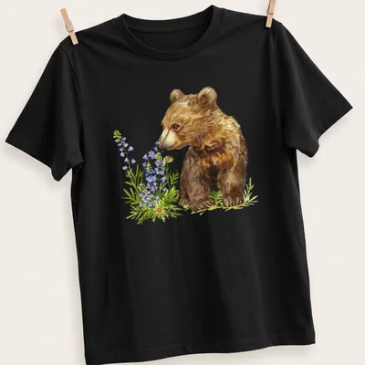 Watercolor bear cub surrounded by vibrant flowers in brown, green, purple, and yellow