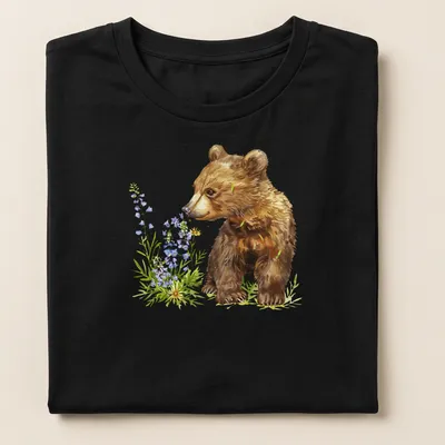 Watercolor bear cub surrounded by vibrant flowers in brown, green, purple, and yellow — printed on a women's shirt