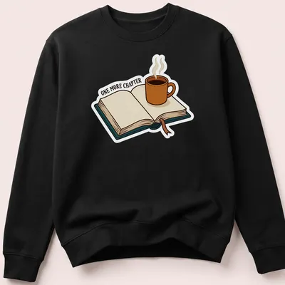 Cartoon design featuring a coffee mug and open book with the text 'ONE MORE CHAPTER' — printed on a unisex sweatshirt