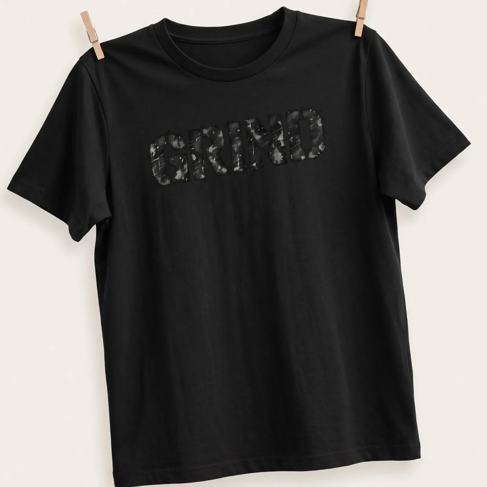 Distressed black and gray t-shirt featuring bold streetwear text that reads 'GRIND' — printed on a unisex t-shirt