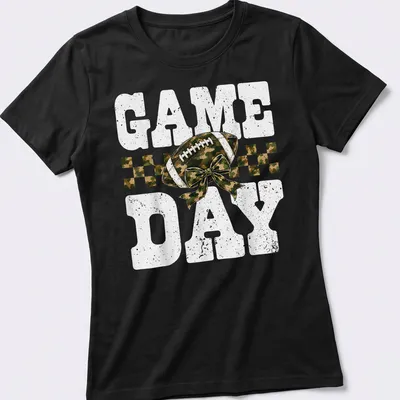 Camo print shirt with playful football and bow graphic, text reads 'GAME DAY' — printed on a women's shirt