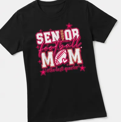 Bold typography Football Mom shirt for Senior 2027, colorful design in pink, white, and gold — printed on a women's shirt