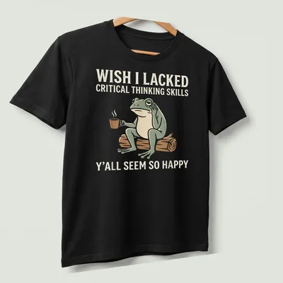 Cartoon frog holding coffee with text about critical thinking skills and happiness — printed on a unisex t-shirt (angled view)