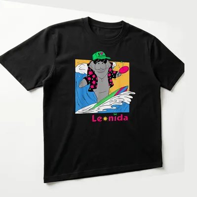 Cartoon manatee surfing with the text 'I ❤️ VACATION' in bright colors — printed on a unisex t-shirt (angled view)