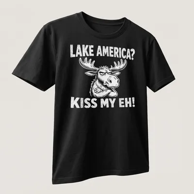 Cartoon moose graphic with the text 'LAKE AMERICA? KISS MY EH!' in black and white — printed on a unisex t-shirt (angled view)