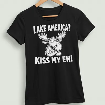 Cartoon moose graphic with the text 'LAKE AMERICA? KISS MY EH!' in black and white — printed on a women's shirt