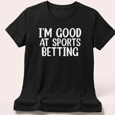Bold typography states 'I'm Good At Sports Betting' in black on white. — printed on a women's shirt
