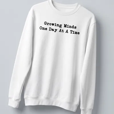 Bold typography Teacher shirt with the phrase Growing Minds One Day At A Time in black — printed on a unisex sweatshirt