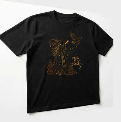Illustrative line-art of a witch with a crow and a magic wand alongside the text 'well, shit...' — printed on a unisex t-shirt (angled view)