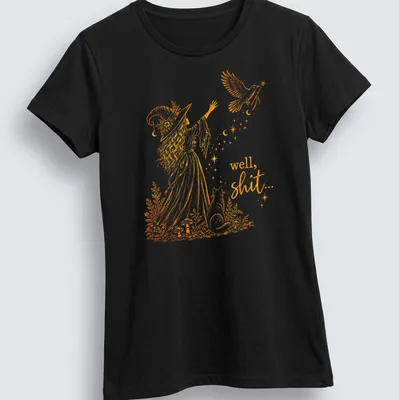 Illustrative line-art of a witch with a crow and a magic wand alongside the text 'well, shit...' — printed on a women's shirt